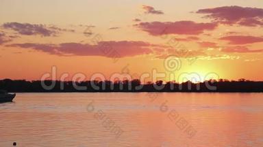 美丽的湖泊景观，海岸线，漂浮的渡船在可爱的橙色日落。